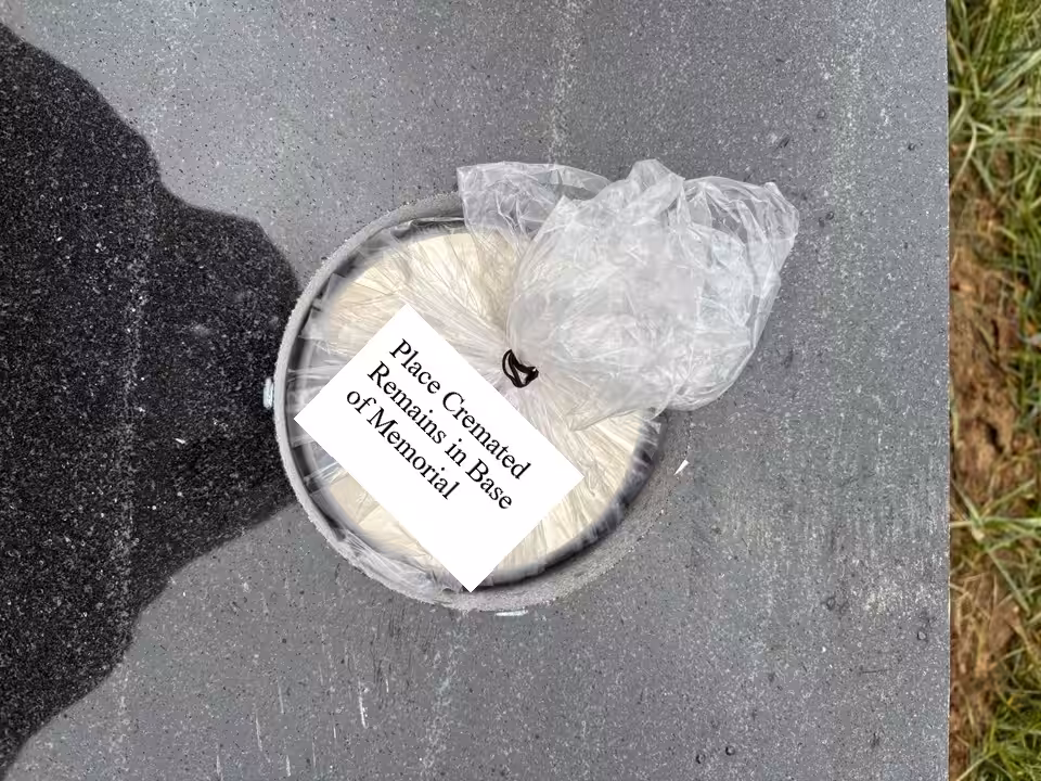 Memorial base with a circular opening containing a bag of cremated remains